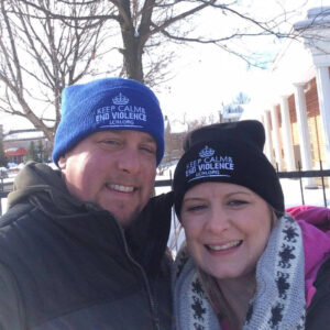 A man and a woman wearing "Keep Calm and End Violence" toques in the winter.